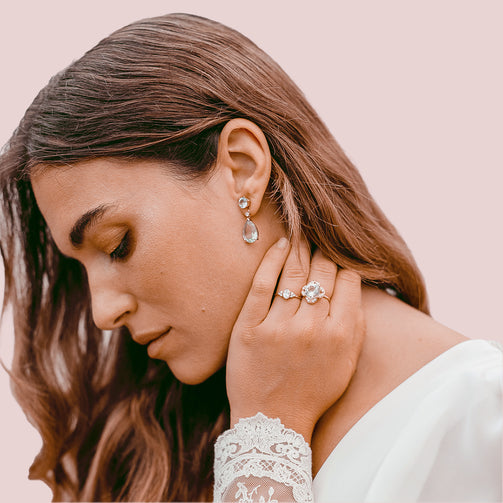Side profile of a bride looking down wearing a white dress with her hand on her neck and her hair down