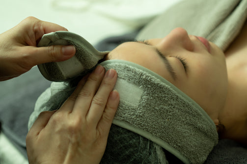 image of a woman lying down as the beauty consultant places a facial headband on her