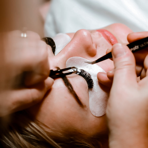 woman lying flat having lash extensions applied