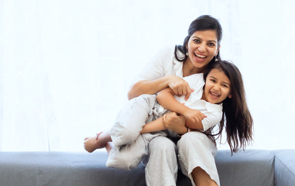 image of a woman in white holding her child in white as they both smile into the camera