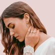 Side profile of a bride looking down wearing a white dress with her hand on her neck and her hair down